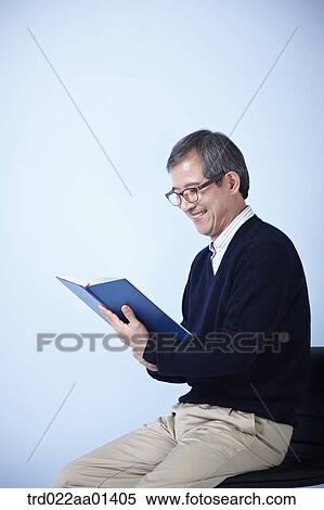 middle aged man reading a book while sitting on a chair View Large Photo Image Stock Photography - middle aged man reading a book while sitting on a chair. Fotosearch