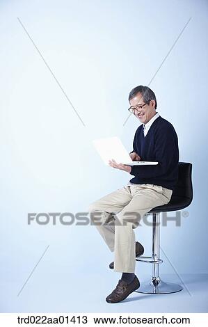 middle aged man using laptop while sitting on a chair View Large Photo Image Stock Image - middle aged man using laptop while sitting on a chair. Fotosearch