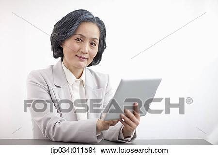 Picture - middle aged woman in business suit using tablet PC. Fotosearch