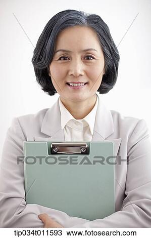 Stock Image - middle aged woman in business suit holding a folder. Fotosearch