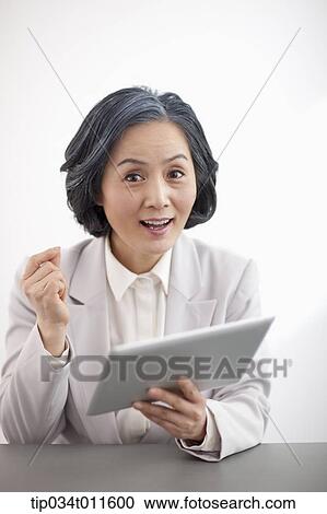 Stock Image - middle aged woman in business suit using tablet PC. Fotosearch