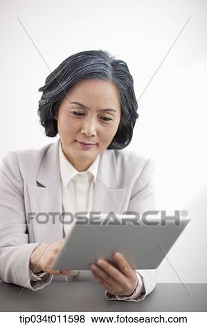 Stock Photo - middle aged woman in business suit using tablet PC. Fotosearch