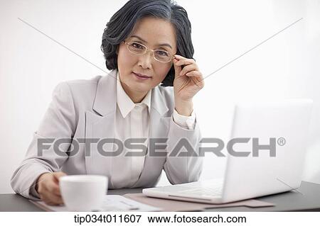 Stock Photo - middle aged woman in business suit using a laptop. Fotosearch