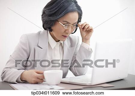 Stock Photo - middle aged woman in business suit using a laptop. Fotosearch