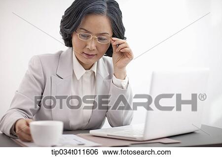 Stock Photograph - middle aged woman in business suit using a laptop. Fotosearch