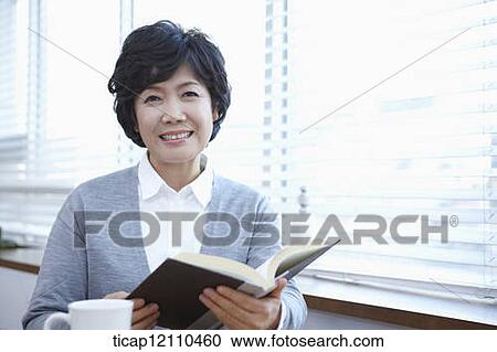 middle aged woman reading a book sitting at table View Large Photo Image Stock Image - middle aged woman reading a book sitting at table. Fotosearch