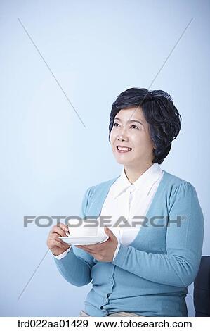 middle aged woman sitting on a chair drinking coffee View Large Photo Image Stock Photo - middle aged woman sitting on a chair drinking coffee. Fotosearch