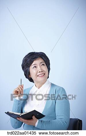 middle aged woman sitting on a chair with a pen and book View Large Photo Image Stock Photography - middle aged woman sitting on a chair with a pen and book. Fotosearch