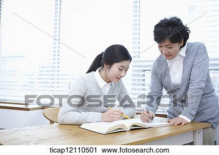 Stock Image - middle aged woman teaching a student . Fotosearch