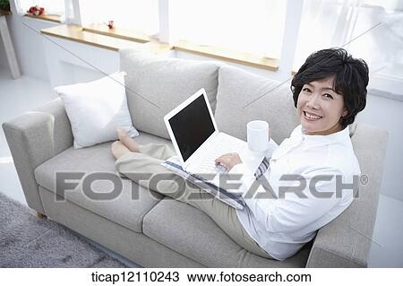 middle aged woman using laptop on a couch View Large Photo Image Stock Image - middle aged woman using laptop on a couch. Fotosearch