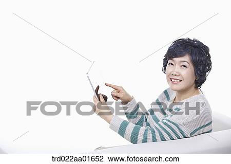 middle aged woman using tablet PC on a couch View Large Photo Image Stock Image - middle aged woman using tablet PC on a couch. Fotosearch
