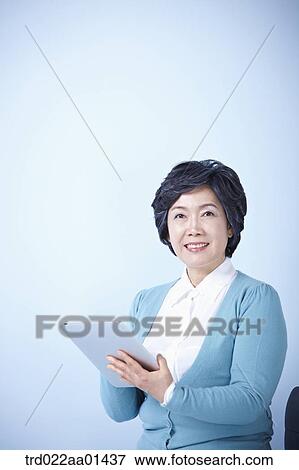 middle aged woman using tablet PC while sitting on a chair View Large Photo Image Stock Photo - middle aged woman using tablet PC while sitting on a chair. Fotosearch
