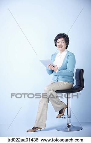 middle aged woman using tablet PC while sitting on a chair View Large Photo Image Stock Photograph - middle aged woman using tablet PC while sitting on a chair. Fotosearch