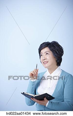 Picture - middle aged woman with a pen and book. Fotosearch