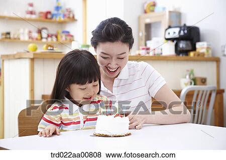 Stock Photo - mother and daughter in front of birthday cake. Fotosearch