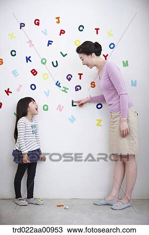 Stock Image - mother and daughter playing with alphabet blocks on the wall. Fotosearch