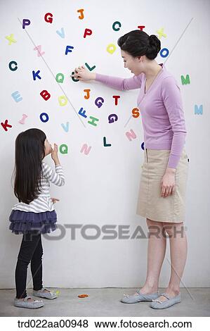 Stock Photo - mother and daughter playing with alphabet blocks on the wall. Fotosearch