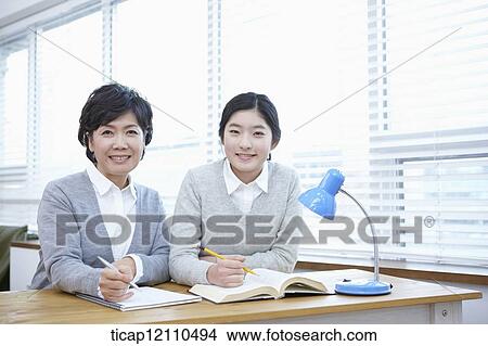 Picture - mother and daughter sitting together in the classroom. Fotosearch