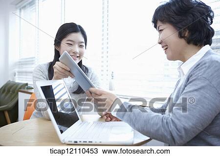 Stock Image - mother and daughter using laptop and tablet PC. Fotosearch