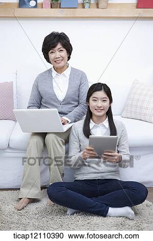 Stock Image - mother and daughter using smart devices. Fotosearch