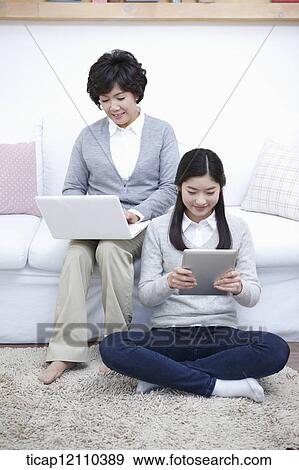 Stock Photo - mother and daughter using smart devices. Fotosearch