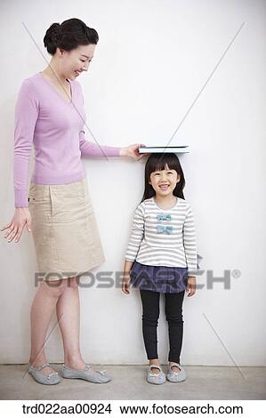 mother measuring daughter's height View Large Photo Image Picture - mother measuring daughter's height. Fotosearch