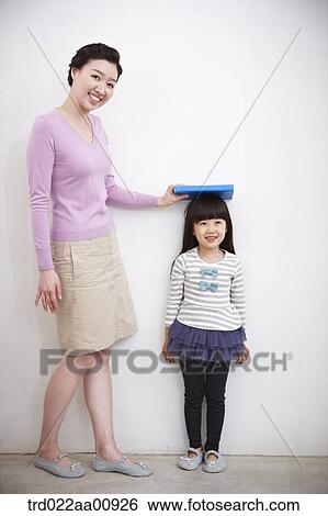 Stock Photograph - mother measuring daughter's height. Fotosearch
