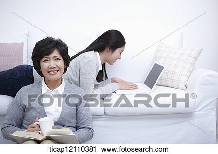 Stock Image - mother next to daughter using laptop on the bed. Fotosearch