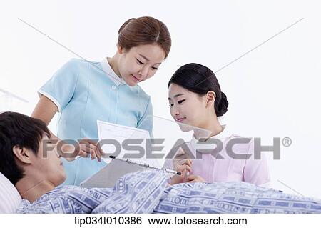 Stock Photograph - nurses taking care of a patient on a bed. Fotosearch