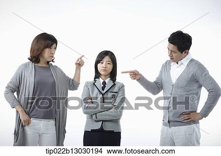 Picture - parents scolding at a daughter with a school uniform. Fotosearch