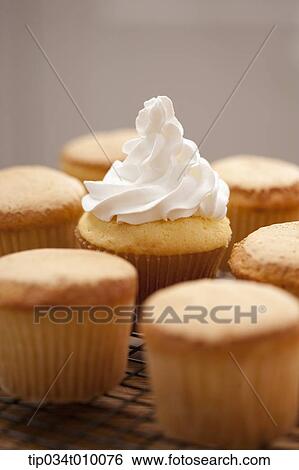 Stock Photograph - putting whip cream on cup cake. Fotosearch