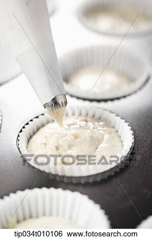 Stock Photograph - putting whip cream on cup cakes. Fotosearch
