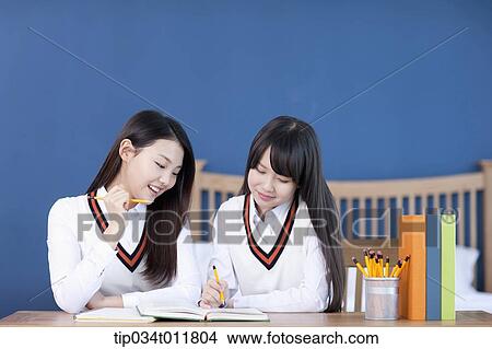 Picture - students in uniform at a desk studying together. Fotosearch