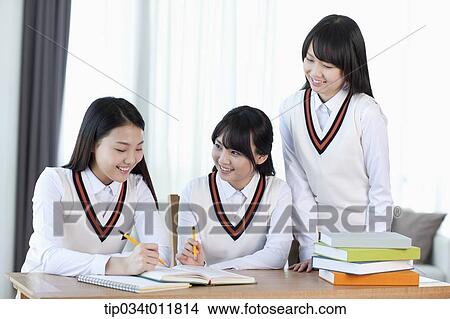 Picture - students in uniform at a desk studying together. Fotosearch
