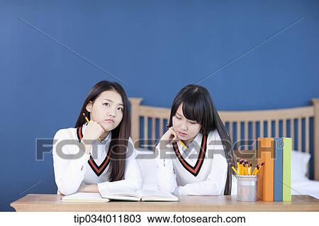 Stock Image - students in uniform at a desk studying together. Fotosearch