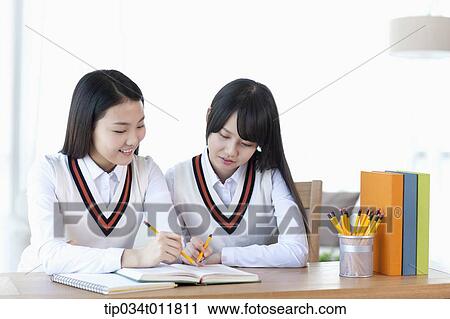 Stock Image - students in uniform at a desk studying together. Fotosearch