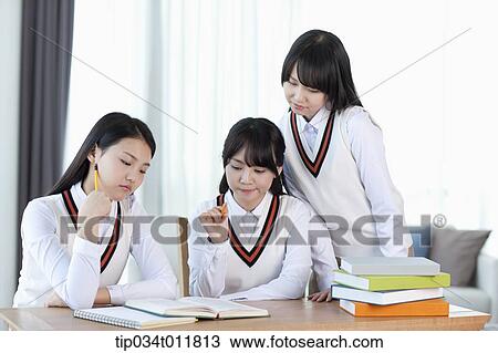 Stock Image - students in uniform at a desk studying together. Fotosearch
