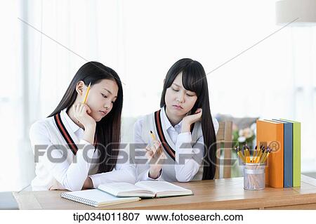 Stock Photo - students in uniform at a desk studying together. Fotosearch