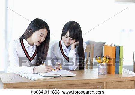 Stock Photo - students in uniform at a desk studying together. Fotosearch