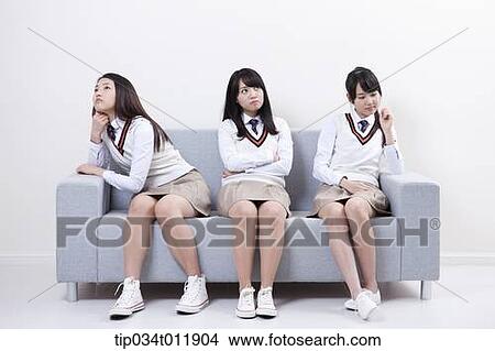 Picture - students in uniform sitting on a couch. Fotosearch