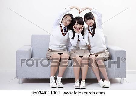 Stock Image - students in uniform sitting on a couch. Fotosearch