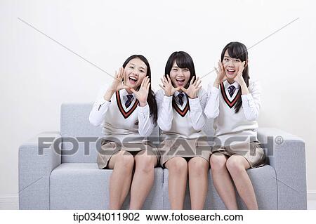 Stock Image - students in uniform sitting on a couch. Fotosearch