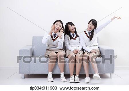 Stock Image - students in uniform sitting on a couch. Fotosearch