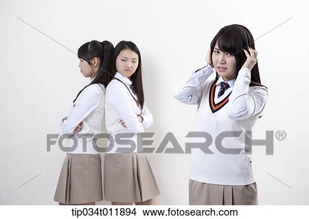 Picture - students in uniform staring at each other. Fotosearch