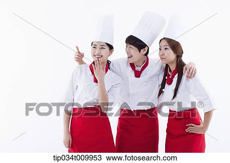 Stock Image - three cook with chef hats looking at same place. Fotosearch