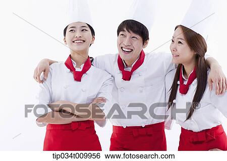 Stock Photograph - three cook with chef hats looking at same place. Fotosearch