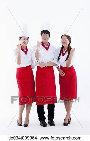 Picture - three cook with chef hats posing cheerfully. Fotosearch
