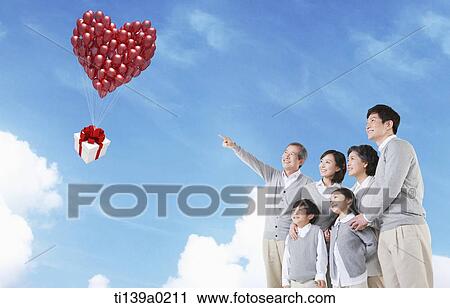 Stock Image - three generations looking at a present flying away. Fotosearch