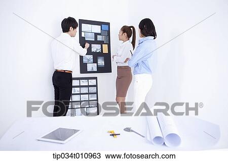 Stock Image - three interior designers working on a portfolio. Fotosearch