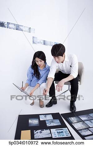 Stock Image - three interior designers working on a portfolio. Fotosearch